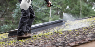 A man applying a chemical treatment to roof moss