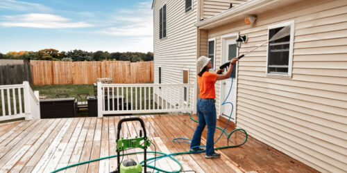 A woman pressure washing the exterior of her house and deck in Southern Oregon