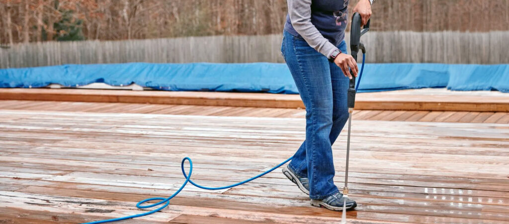 A homeowner using a rented pressure washer on a deck
