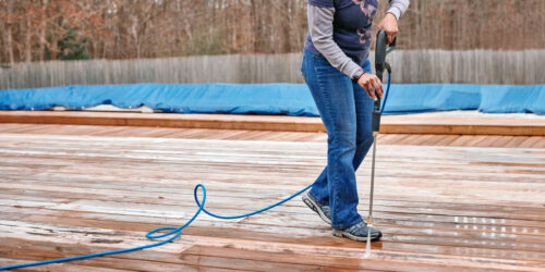 A homeowner using a rented pressure washer on a deck